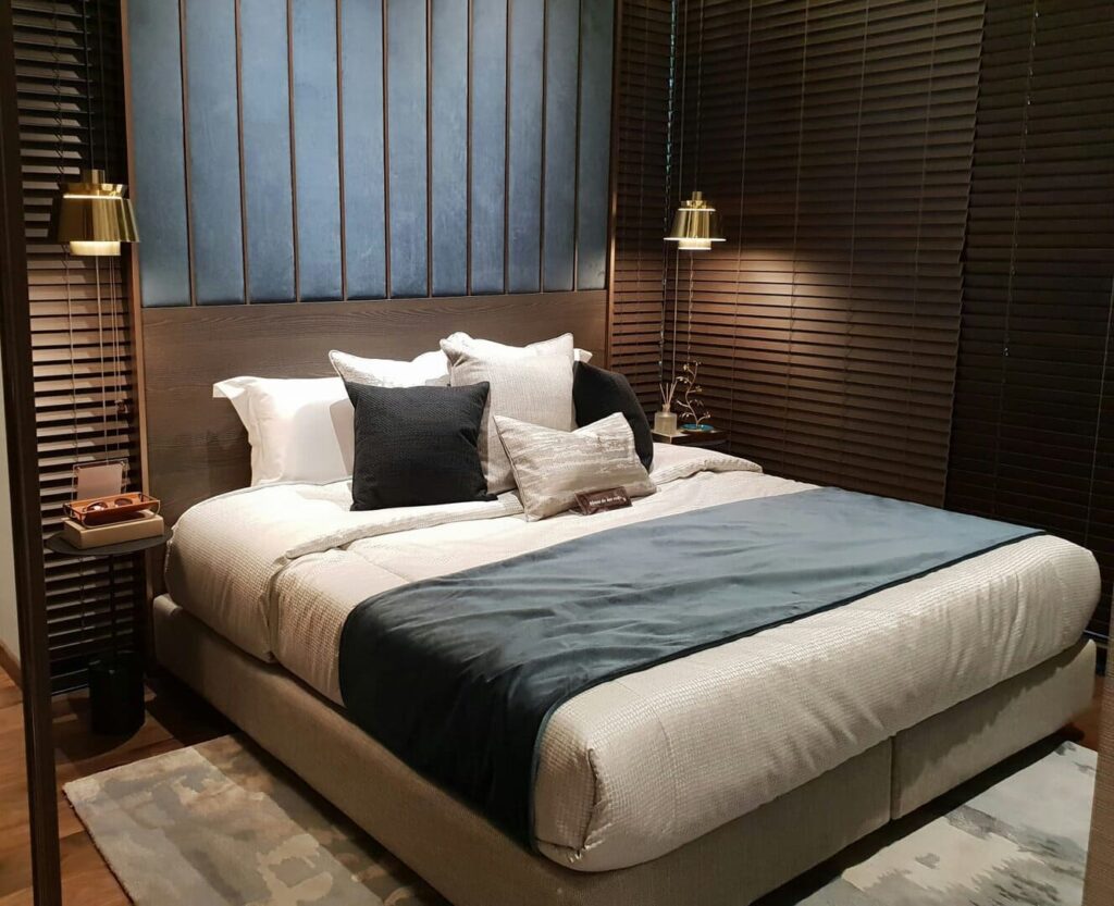 Nowoczesna sypialnia z stylowym zagłówkiem i lampami, projekt Moniki Grala prezentuje elegancki i funkcjonalny wystrój wnętrza.