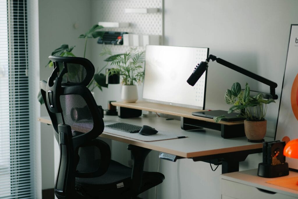 Ergonomiczne biurko w domu z roślinami i sprzętem komputerowym, idealne do pracy i nauki.
